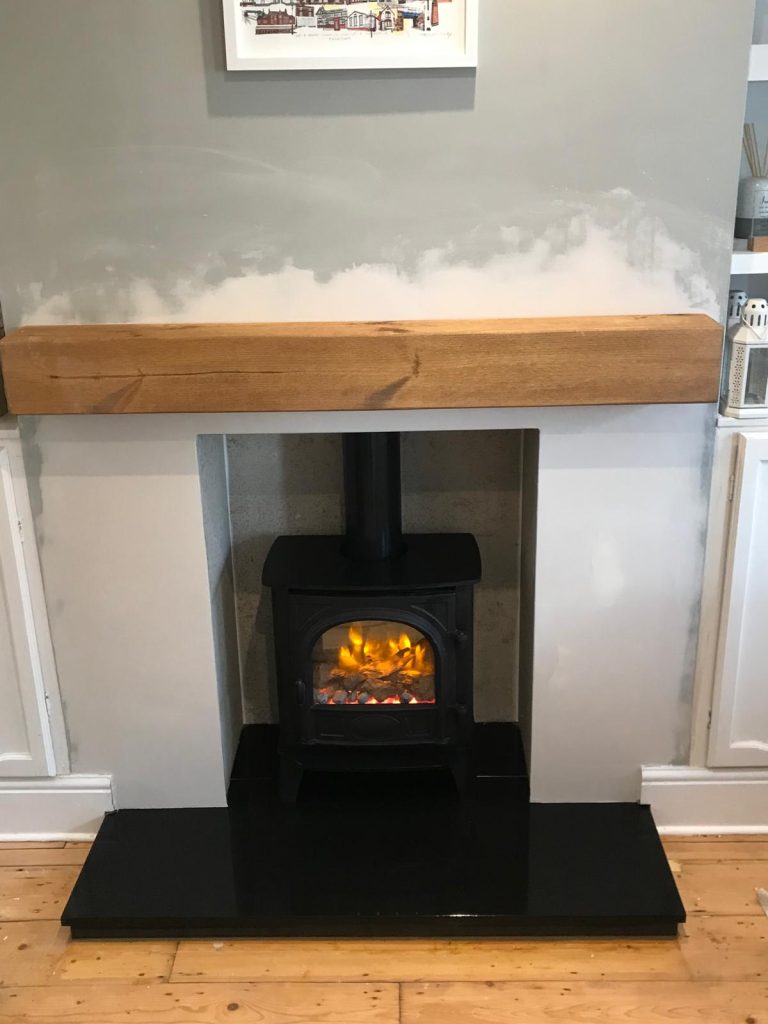 Electric stove with oak beam and black hearth, installed by Fire Flair Direct