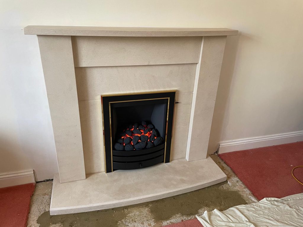 Inset gas fire in a cream stone fireplace, installed by Fire Flair Direct
