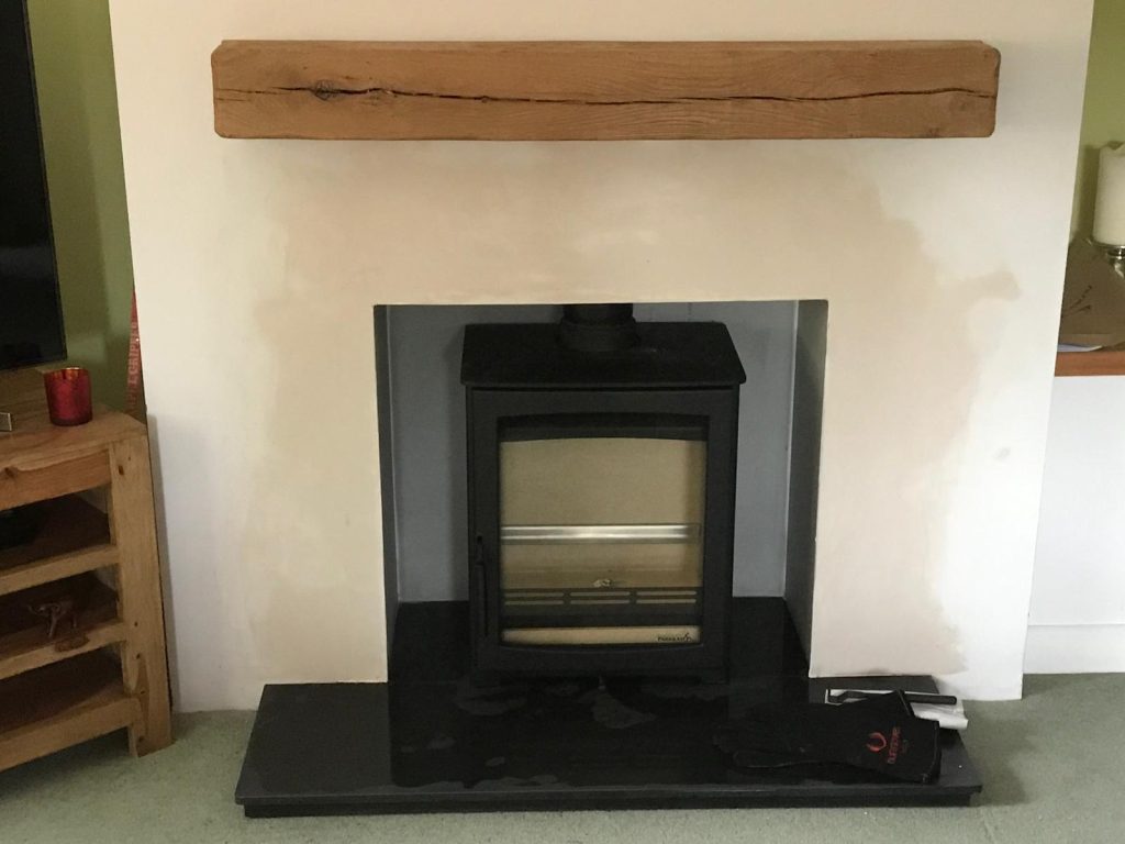 Wood-burning stove with oak beam and slate hearth, installed by Fire Flair Direct